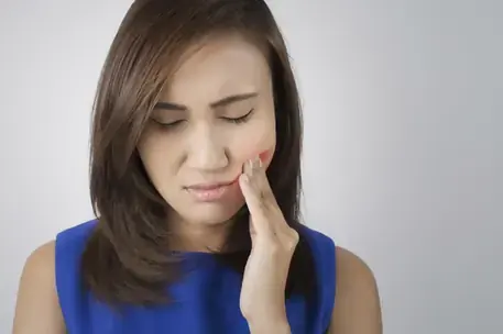 A patient holding her jaw in discomfort from a TMJ disorder